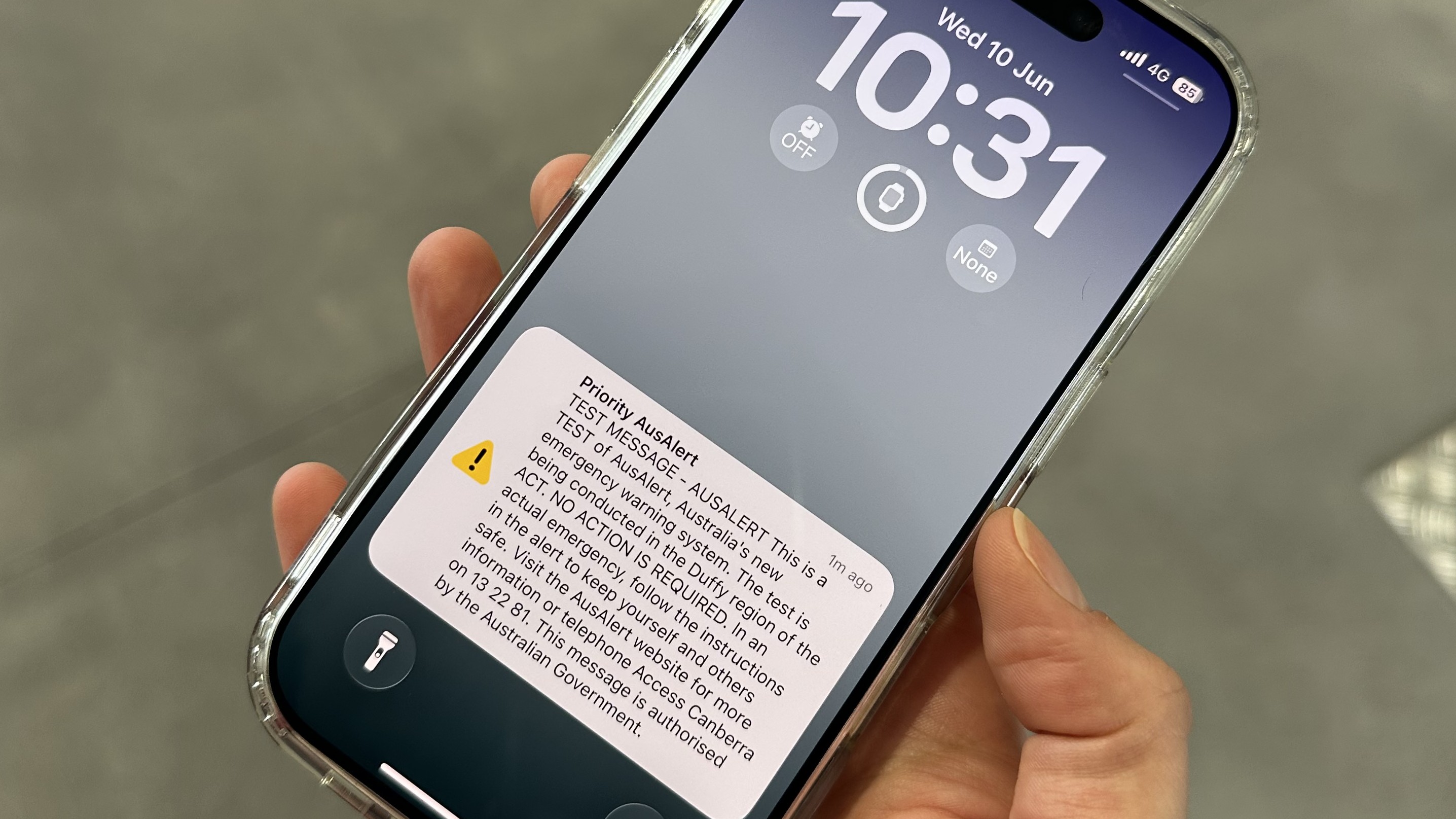 Photo of a hand holding a smartphone that shows the time 10:31 and a test AusAlert notification on the screen.