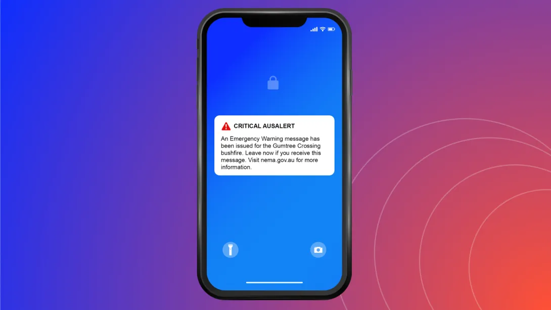 Mockup of a phone with message: CRITICAL AUSALERT. An Emergency Warning message has been issued for the Gumtree Crossing bushfire. Leave now if you receive this message. Visit nema.gov.au for more information.